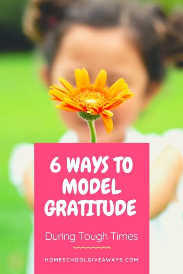image of child holding orange flower with text ovelay. 6 ways to model gratitude during tough times. www.HomeschoolGivaways.com