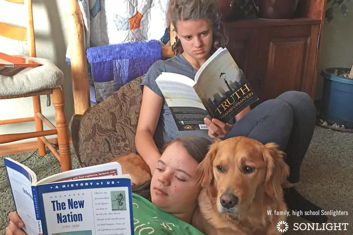 two kids reading books together next to a dog