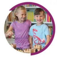 two kids smiling and playing with toys together and a background of bookshelves