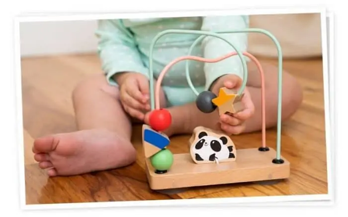 a little child playing with a toy sitting on a wooden floor