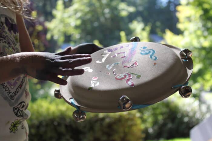 A child hitting a tambourine outside