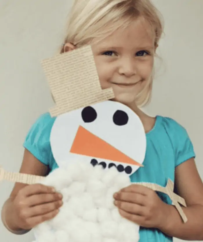Child holding a paper snowman craft
