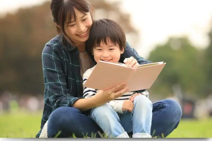  mom and young son reading book outside