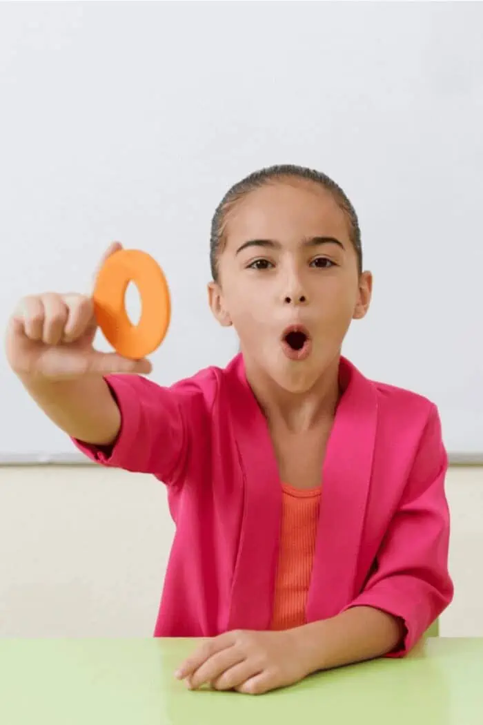 A girl holding up the letter o.