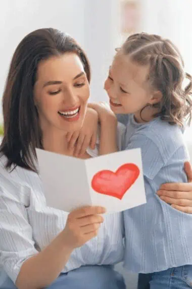A Mom with her daughter smiling and reading a card